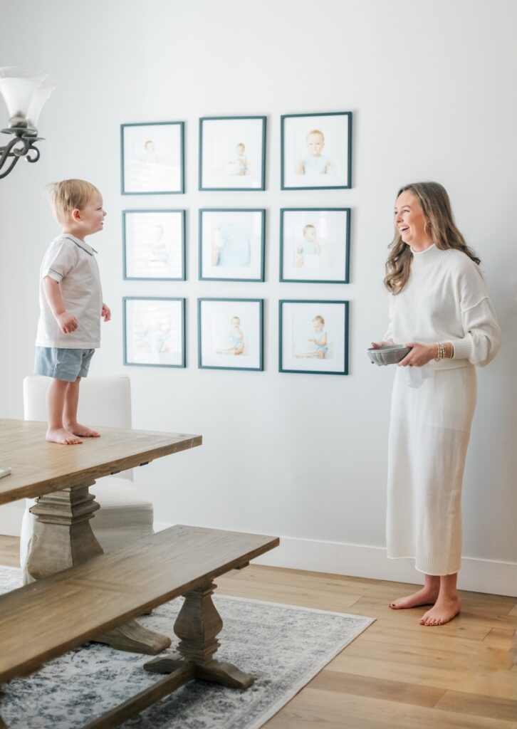 child standing on table looking at mom as she walks into dining room holding bowl of candy