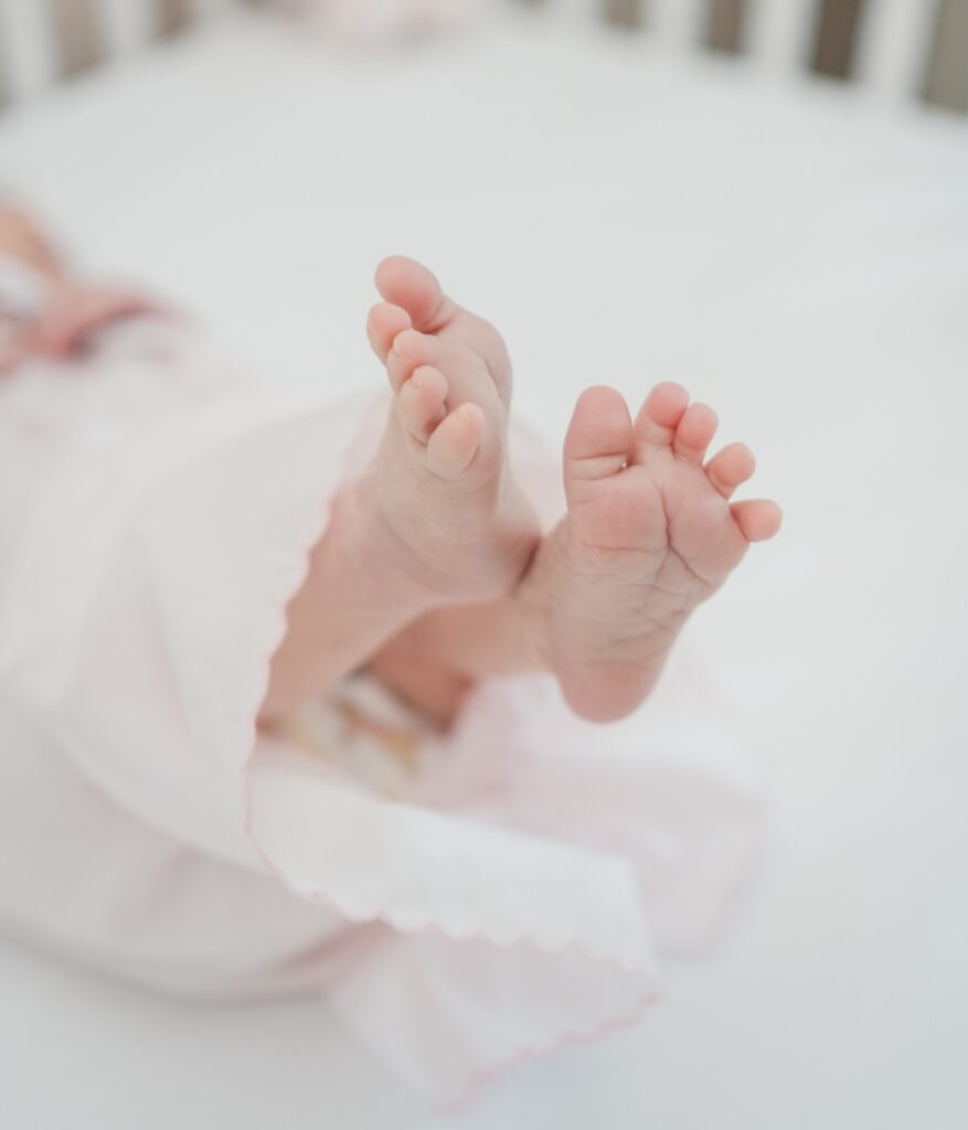 photo of newborn baby girl feet with timeless soft pink gown