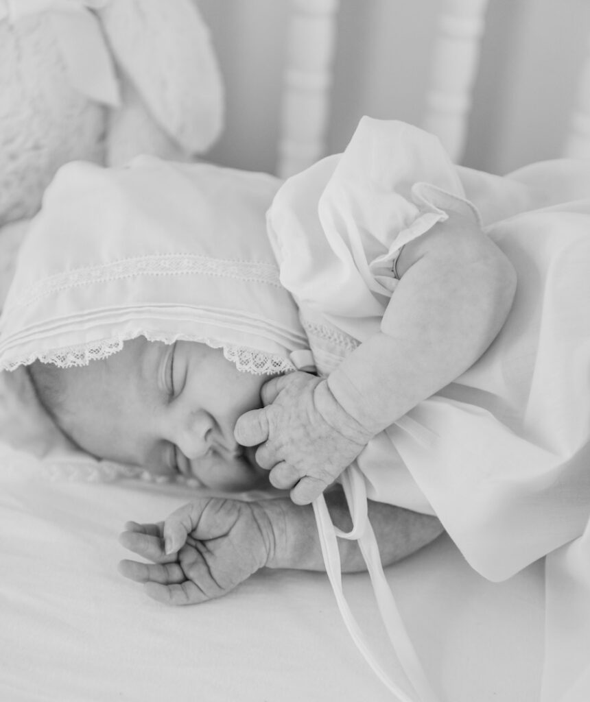 black and white photo of newborn baby girl laying in crib asleep