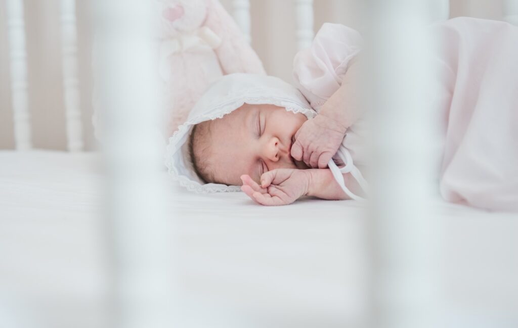 photo of newborn baby girl laying in crib asleep