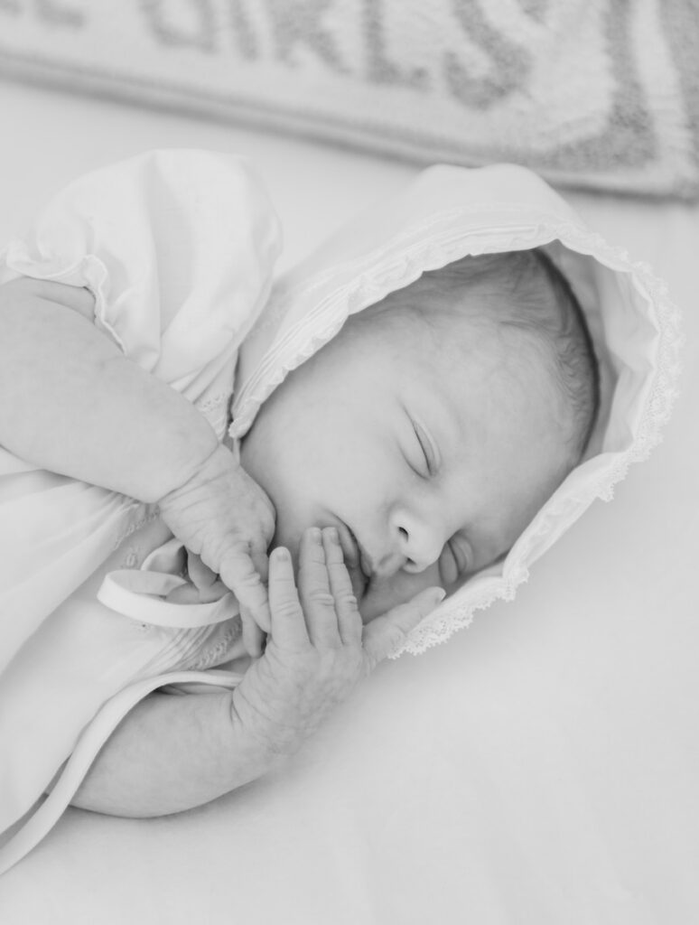 black and white photo of newborn baby girl laying in crib asleep