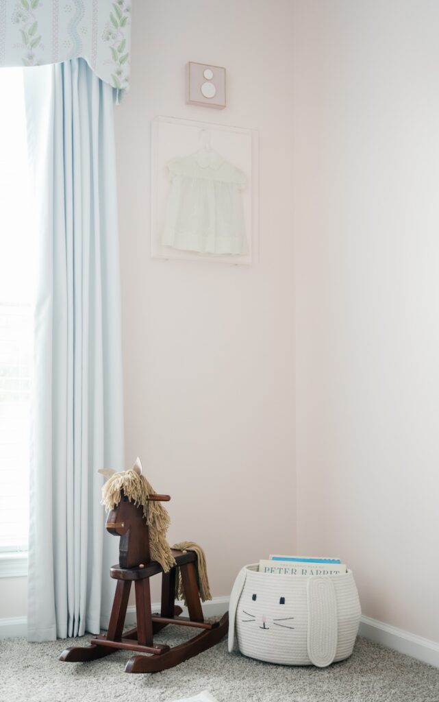 photo of the corner of the nursery with a bunny basket of books and wooden rocking chair